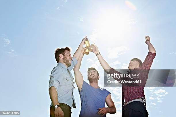 germany, cologne, young men drinking beer - celebratory toast stock-fotos und bilder