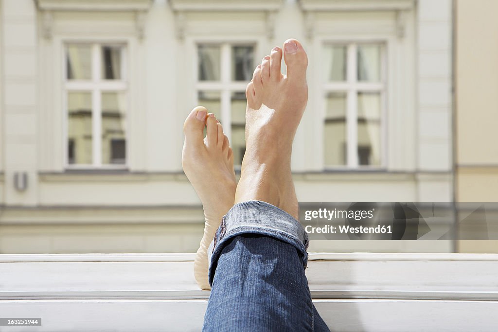 Germany, Berlin, Young woman feets on open window