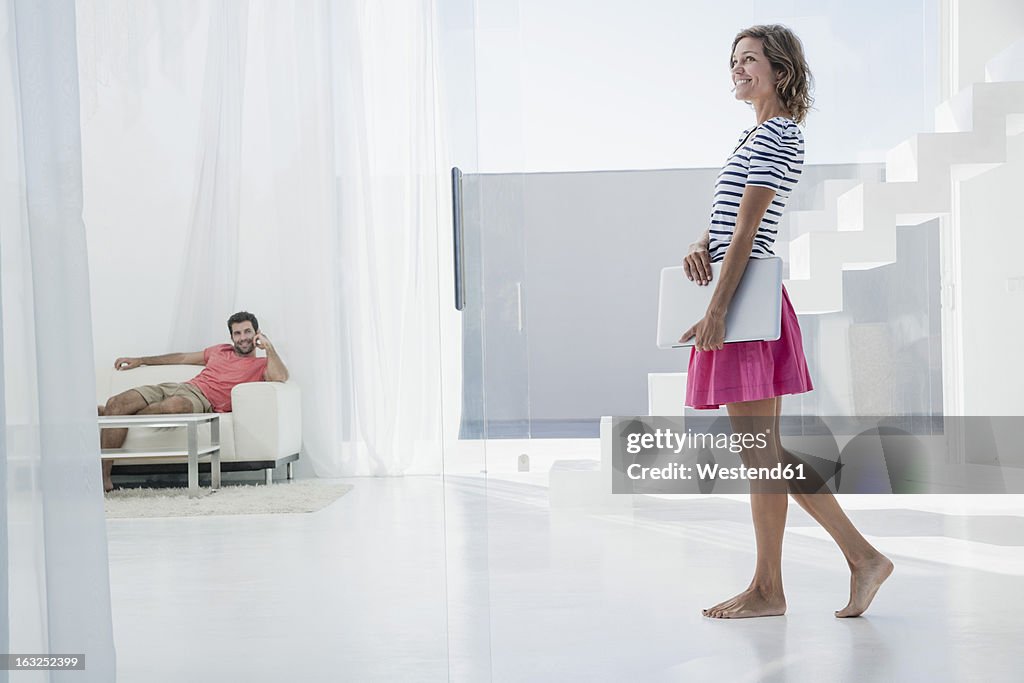 Spain, Mid adult couple with laptop in modern apartment