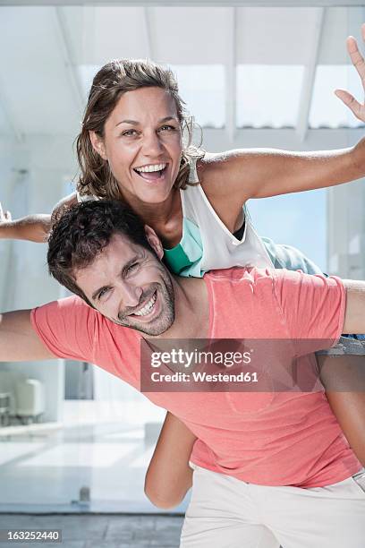 spain, mid adult man giving piggy back ride to woman, smiling - 飛行機のまね ストックフォトと画像