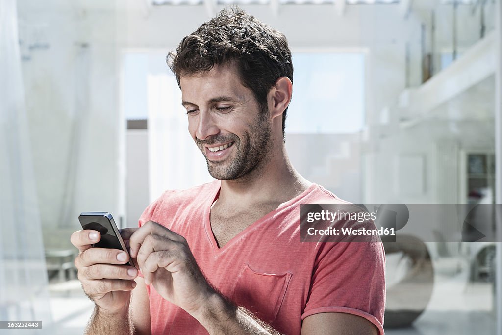 Spain, Mid adult man using cell phone, smiling