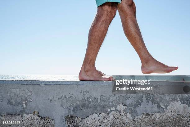 spain, mid adult man walking on wall - barefoot men - fotografias e filmes do acervo