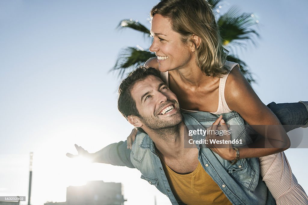 Spain, Mid adult man giving piggy back ride to woman