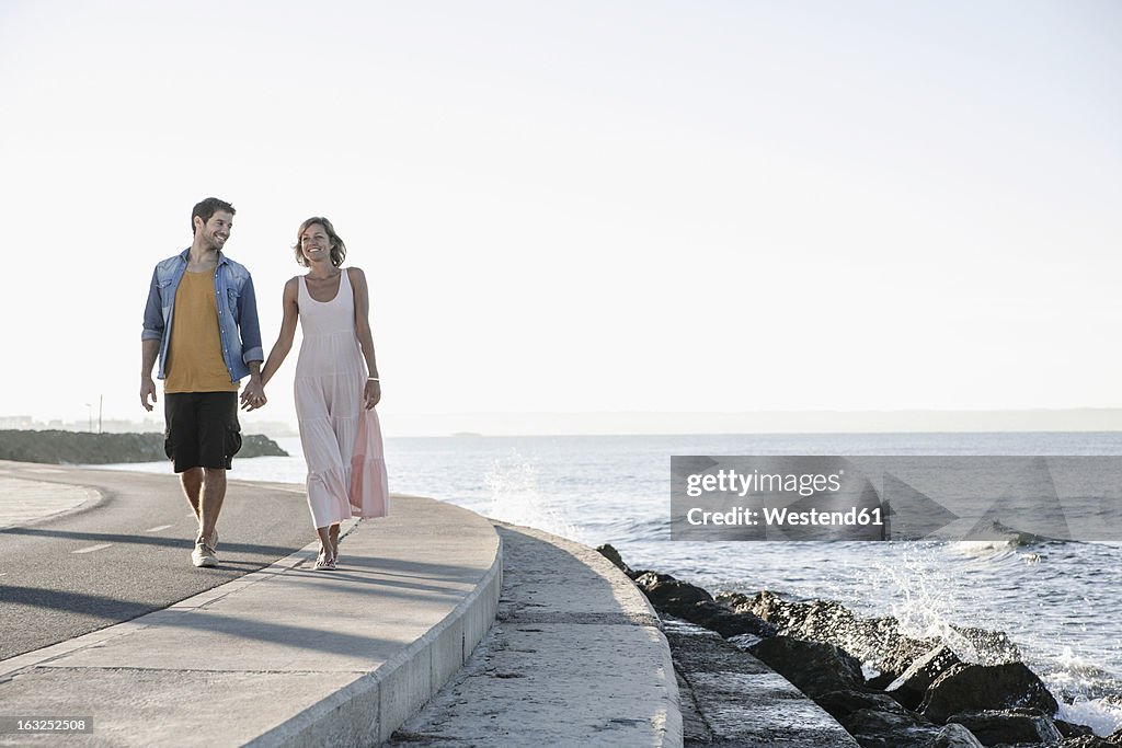 Spain, Mid adult couple walking along coast