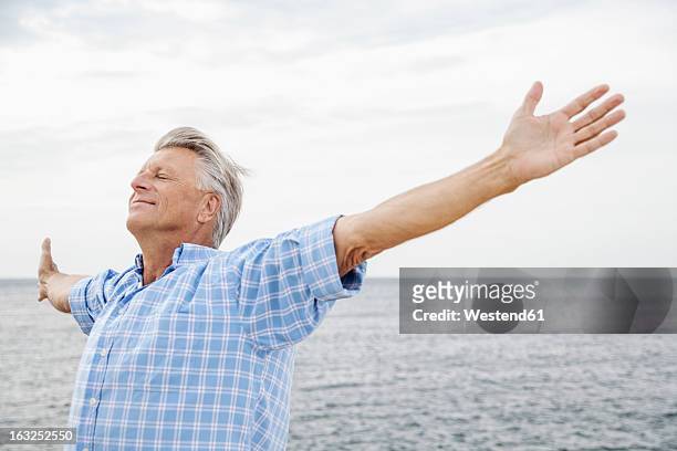 spain, senior man stretching on beach - westend61 fotografías e imágenes de stock