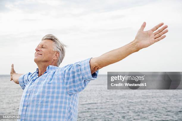 spain, senior man stretching on beach - man arms raised stock pictures, royalty-free photos & images