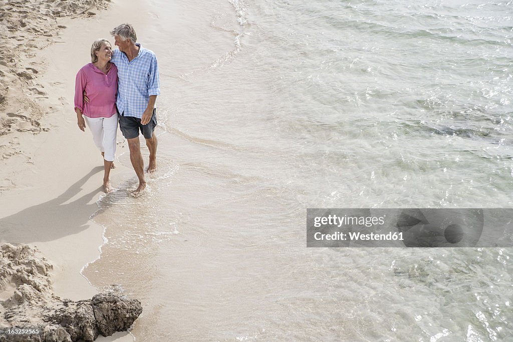 Spain, Seniors couple walking along beach