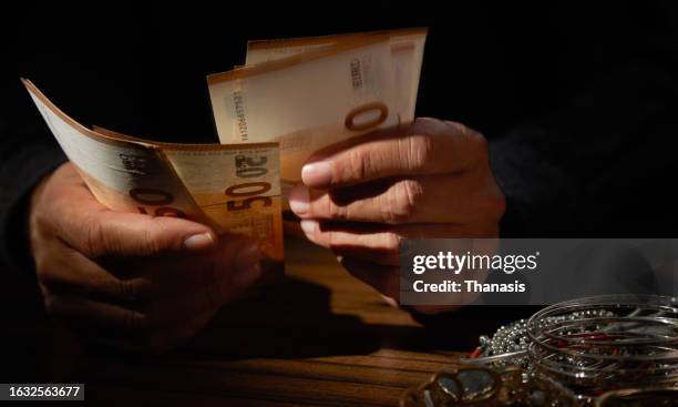 close-up of a person's hand counting money, in front of a pile of stolen goods - jewelry robbery stock pictures, royalty-free photos & images