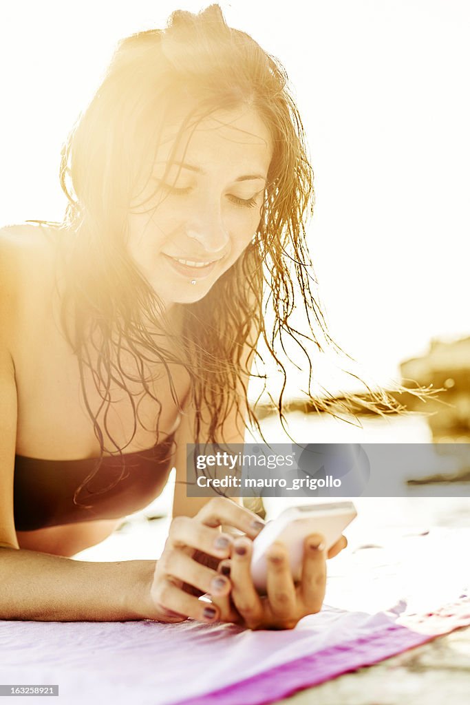 女性の携帯電話を使用するオンザビーチ