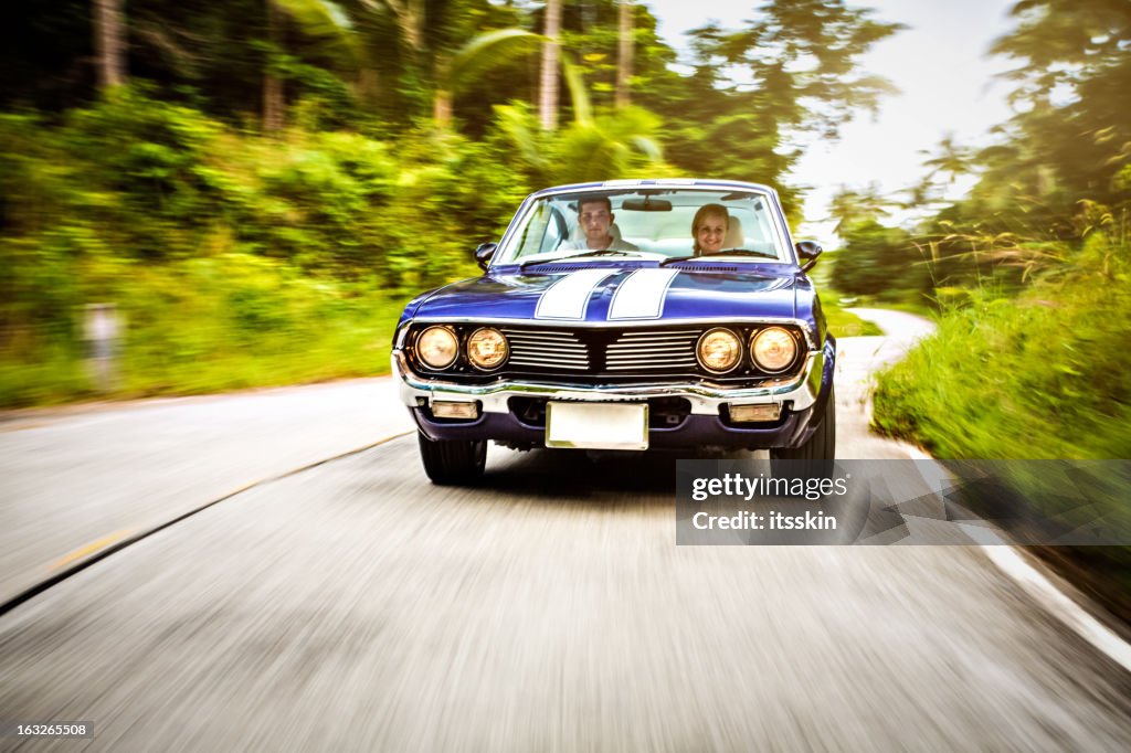 Couple driving retro car down the road