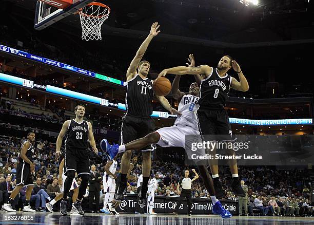 Teammates Brook Lopez and Deron Williams of the Brooklyn Nets knock the ball loose from Bismack Biyombo of the Charlotte Bobcats during their game at...