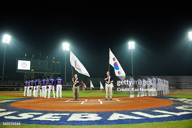 Members of Team Chinese Taipei and Team Korea are seen on the base paths during the playing of the National Anthems before Pool B, Game 6 between...