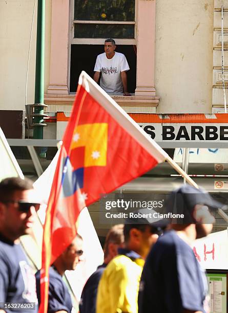 Man looks out his window as protesters walk through the city during a union organised protest against temporary worker visas on March 7, 2013 in...