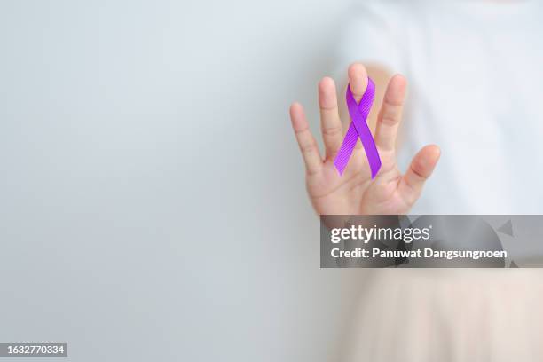 Woman holding purple Ribbon for Violence, Pancreatic, Esophageal, Testicular cancer, Alzheimer, epilepsy, lupus, Sarcoidosis and Fibromyalgia. Awareness month and World cancer day concept
