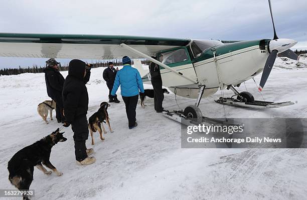 Iditarod volunteers load dropped dogs into the plane of Iditarod Air Force pilot Danny Davidson at Nikolai, Alaska, airport on Wednesday, March 6...