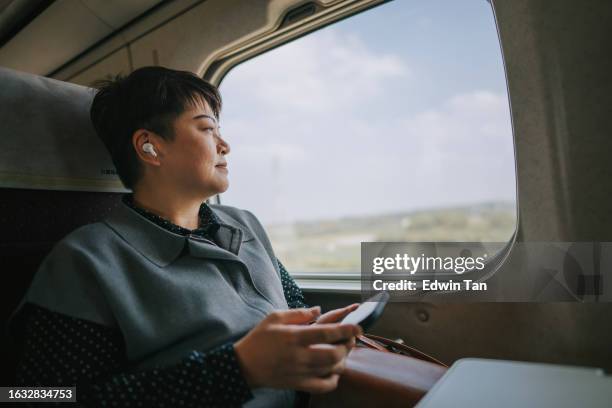 alleinreisen asiatische chinesische reife frau reisen im hochgeschwindigkeitszug nach kaohsiung - elektrischer zug stock-fotos und bilder