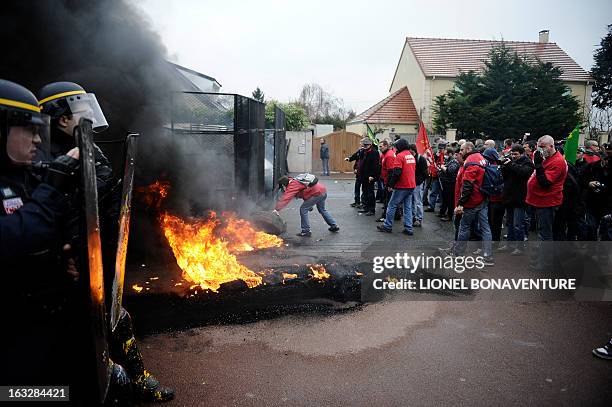 Protesting Goodyear France workers face riot police in front of the French headquarters of the the US tyre and rubber firm in the western Paris...