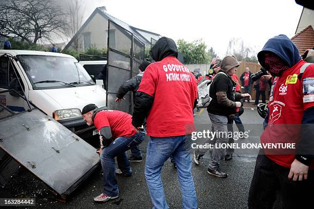 Protesting Goodyear France workers remove riot police barriers in front of the French headquarters of the the US tyre and rubber firm in the western...