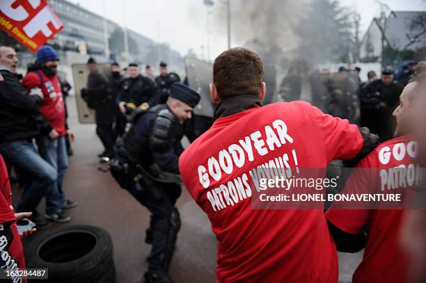 Protesting Goodyear France workers face riot police in front of the French headquarters of the the US tyre and rubber firm in the western Paris...