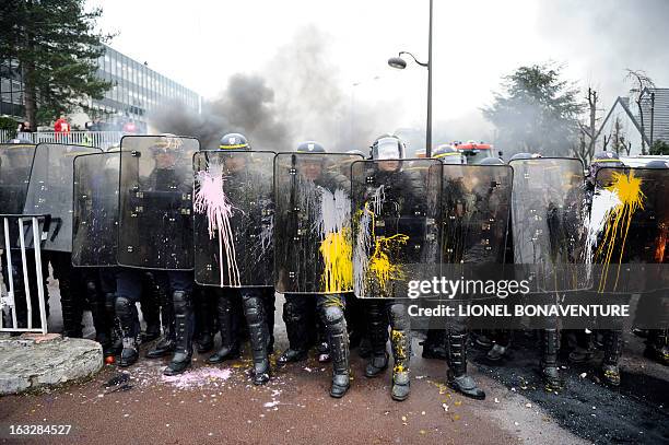 French riot police shield themselves against paint thrown by protesting Goodyear France workers in front of the French headquarters of the the US...