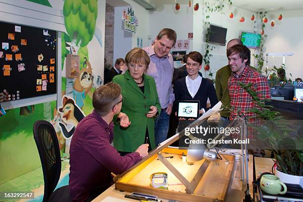 German Chancellor Angela Merkel speaks with graphic artist Gerben Steenks , during guided tour by the general manager Jens Begemann in the Wooga...