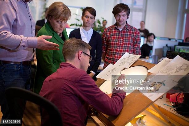 German Chancellor Angela Merkel , watches employee Gerben Steeks , during a visit of the Wooga company, which makes social games for smartphones and...