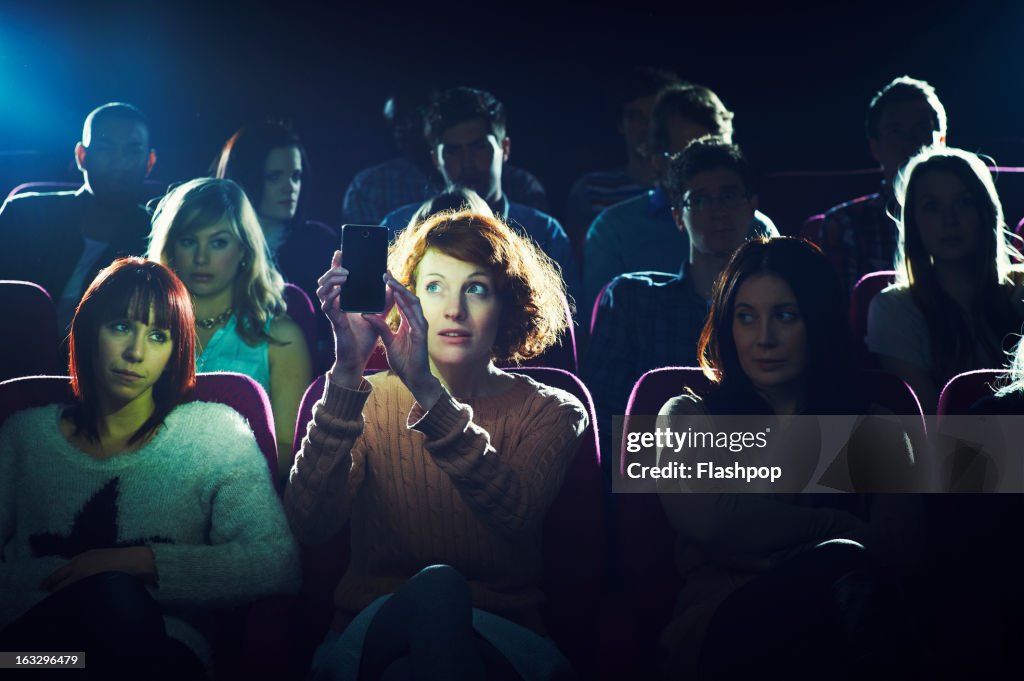 Woman using phone during movie at cinema