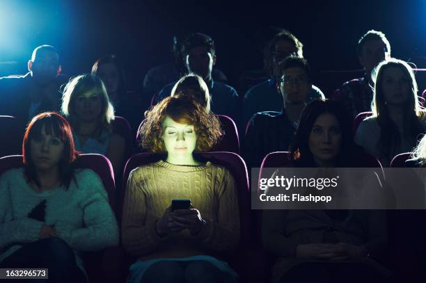 woman using phone during movie at cinema - bot stockfoto's en -beelden