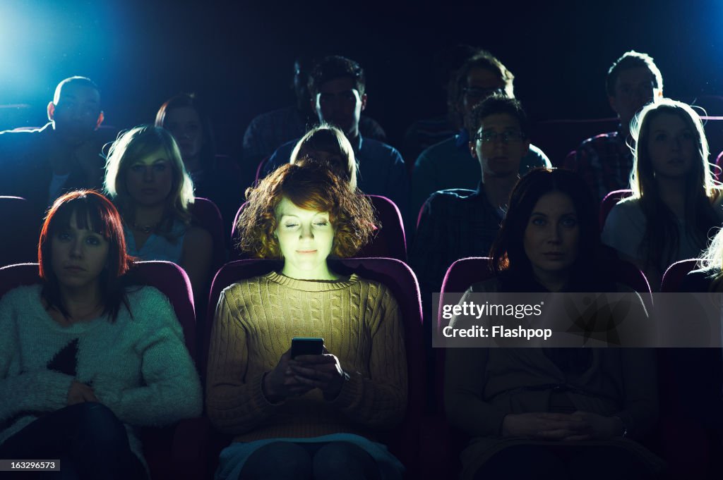 Woman using phone during movie at cinema