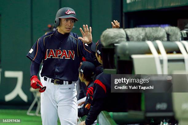 Takashi Toritani of Team Japan is greeted in the dugtout after scoring a run during the 2013 World Baseball Classic exhibition game against the...