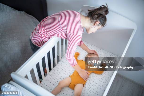 une mère attentionnée endormant son petit garçon. - heure du coucher photos et images de collection