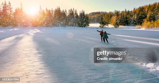 couple skating on frozen lake - holding hands in the snow stock pictures, royalty-free photos & images