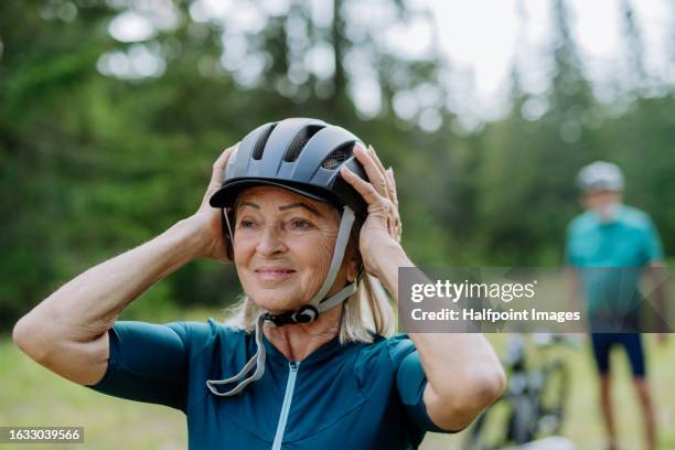 portrait of senioelderly cyclist adjusting and fitting bicycle helmet. - laccio foto e immagini stock