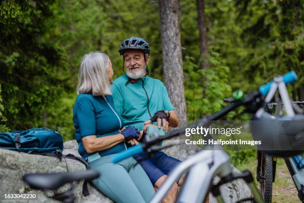 elderly cyclist resting, having healthy snack to gain energy. - fahrrad fahren alte leute beine stock-fotos und bilder