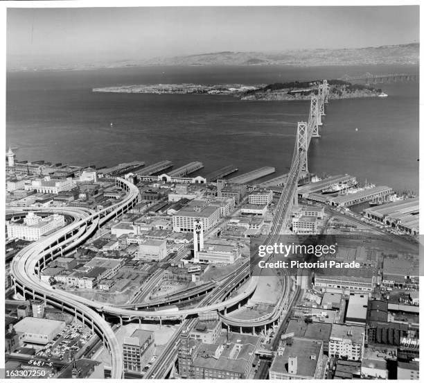 View of the San Francisco-Oakland Bay Bridge stretching for miles, as the buildings, streets and docks enclose the bridge before it extends over the...