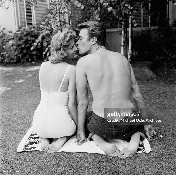 Maggie Johnson, wearing a swimsuit, is kissed on the nose by her husband, American actor and film director Clint Eastwood, in the garden of their...