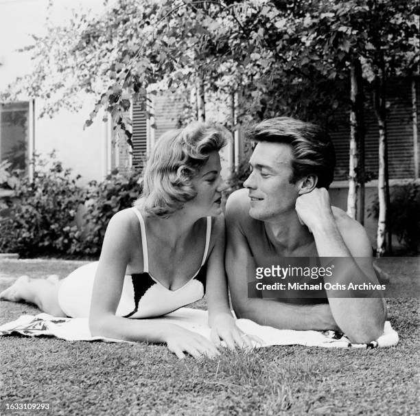 Maggie Johnson, wearing a swimsuit, and her husband, American actor and film director Clint Eastwood, gaze into each other's eyes in the garden of...