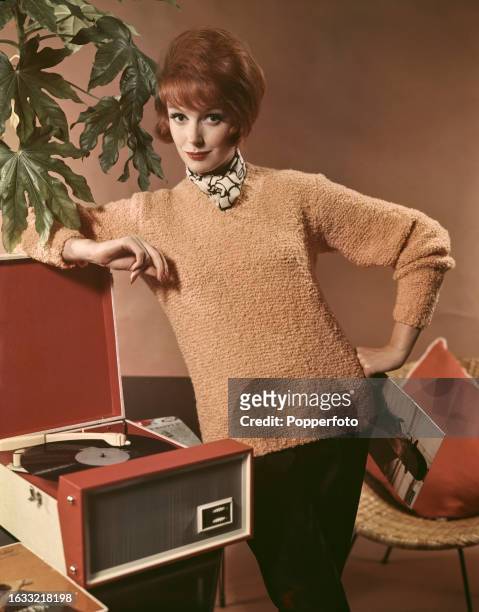 Posed studio portrait of a female fashion model wearing a bold knit V-neck jersey sweater in coffee cream colour with a cream and black neck scarf...