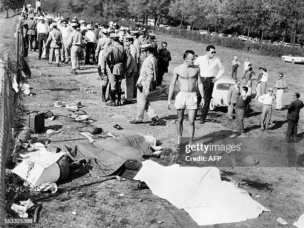 Dead bodies lie on the ground as policemen try to evacuate people from the scene of the accident caused by German driver Wolfgang von Trips, whose...