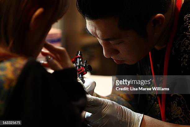 Young woman is tattooed during The Australian Tattoo & Body Art Expo at the Royal Hall of Industries, Moore Park on March 8, 2013 in Sydney,...