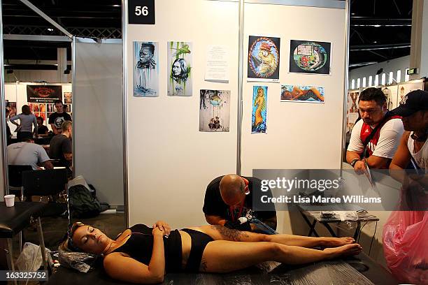 Young woman has her leg tattooed by artist Anthony Orsatti of 'Skintastic' during The Australian Tattoo & Body Art Expo at the Royal Hall of...