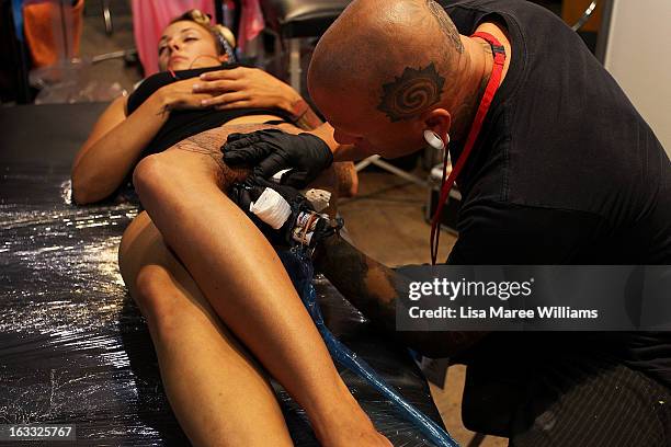 Young woman has her leg tattooed by artist Anthony Orsatti of 'Skintastic' during The Australian Tattoo & Body Art Expo at the Royal Hall of...