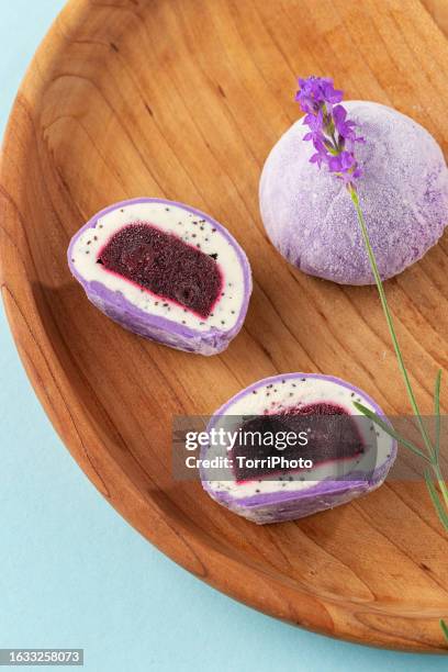 traditional daifuku mochi with lavander flavor and bluberry filling on wooden tray. cut in half dessert on blue background - bluberry imagens e fotografias de stock