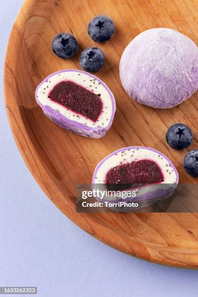 traditional daifuku mochi with lavander flavor and bluberry filling on wooden tray. cut in half dessert on purple background - bluberry imagens e fotografias de stock