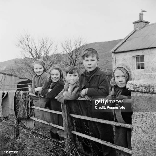 Five children lean on railings ourtside a farmhouse on the Isle of Harris in the Outer Hebrides of Scotland on 12th February 1946.