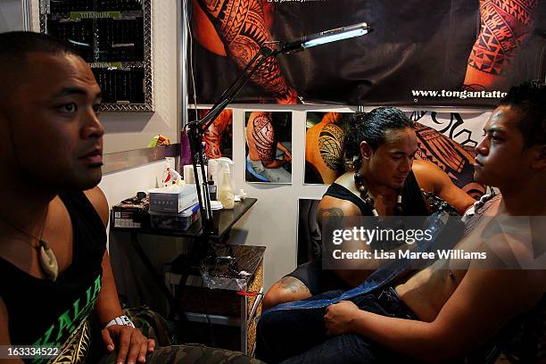 Tattoo artist Carl Cocker of 'Kalia Tattoo NZ' works on a young man during The Australian Tattoo & Body Art Expo at the Royal Hall of Industries,...