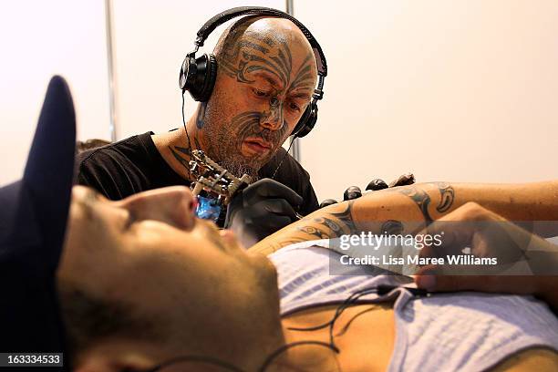 Tattoo artist Turumakina tattoos a young man's arm during The Australian Tattoo & Body Art Expo at the Royal Hall of Industries, Moore Park on March...