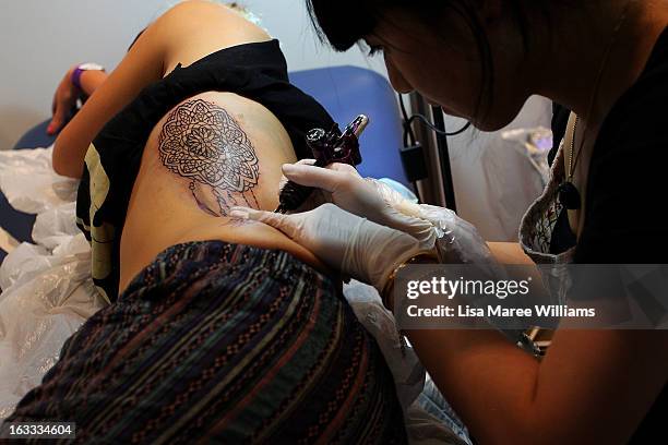 Young woman is tattooed during The Australian Tattoo & Body Art Expo at the Royal Hall of Industries, Moore Park on March 8, 2013 in Sydney,...