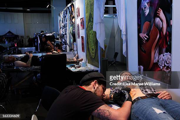 Tattoo artist Jimi May works on a woman's stomach during The Australian Tattoo & Body Art Expo at the Royal Hall of Industries, Moore Park on March...