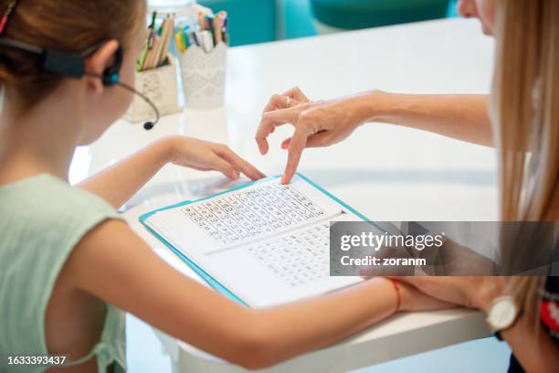 audiometry session, girl reading material assisted by practitioner - speech pathology stock pictures, royalty-free photos & images